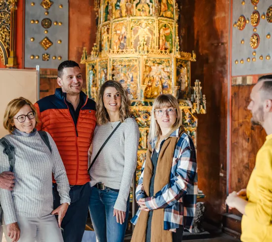 Gruppe von Touristen hört einem Guide in einem historischen prunkvollen Gebäude zu